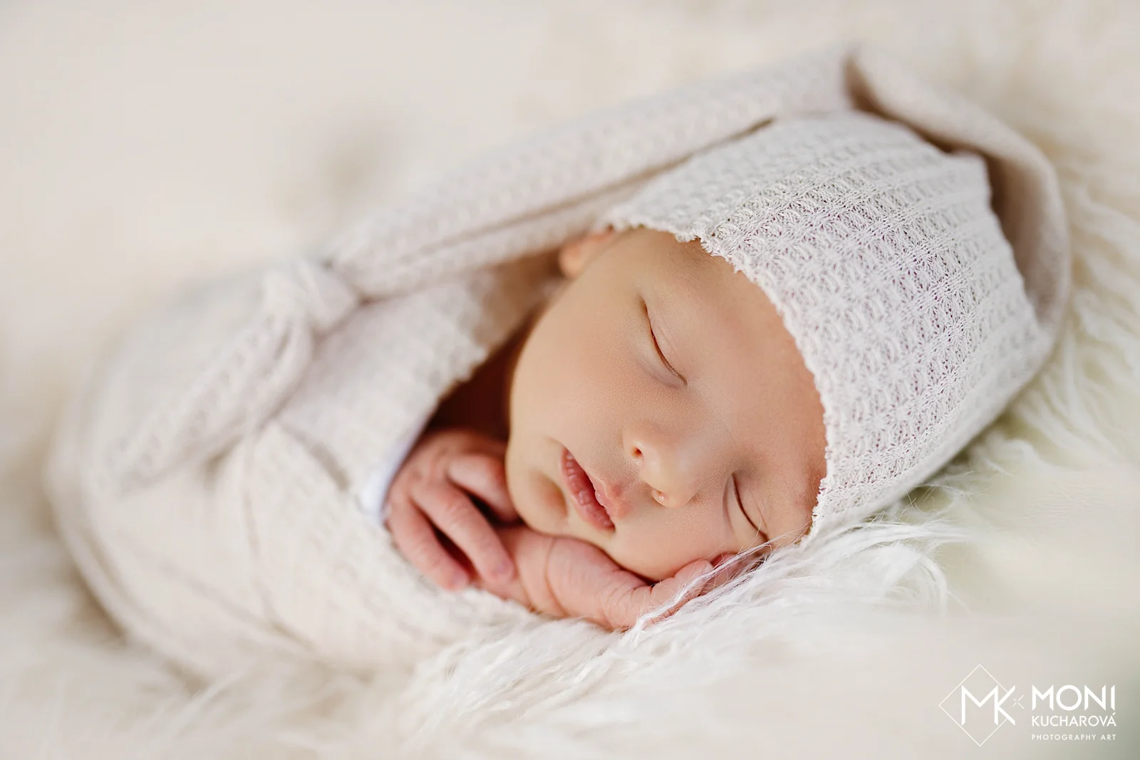 Detail spiaceho bábätka v svetlej pletenej čiapke a jemnej zavinovačke